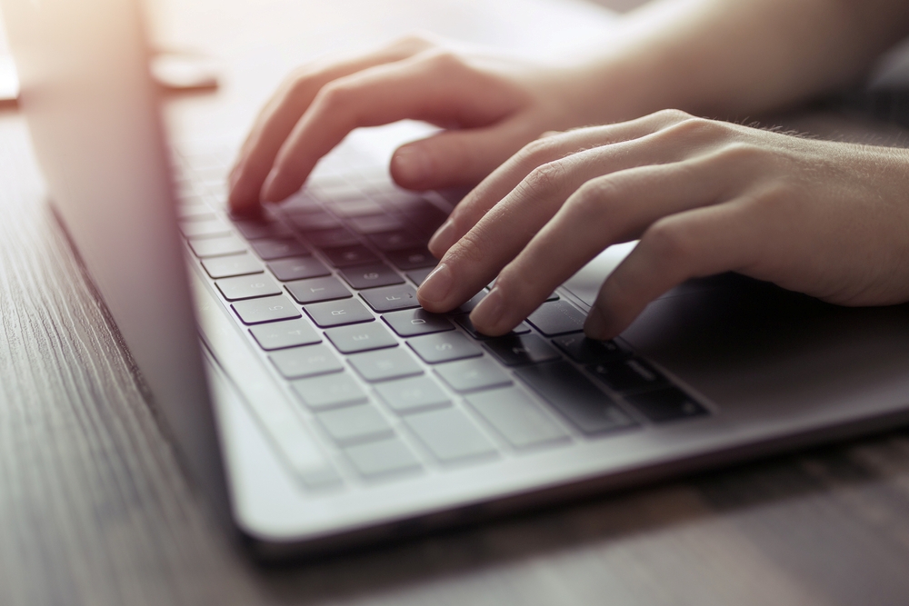 `alt="Hands operating a computer for research."`