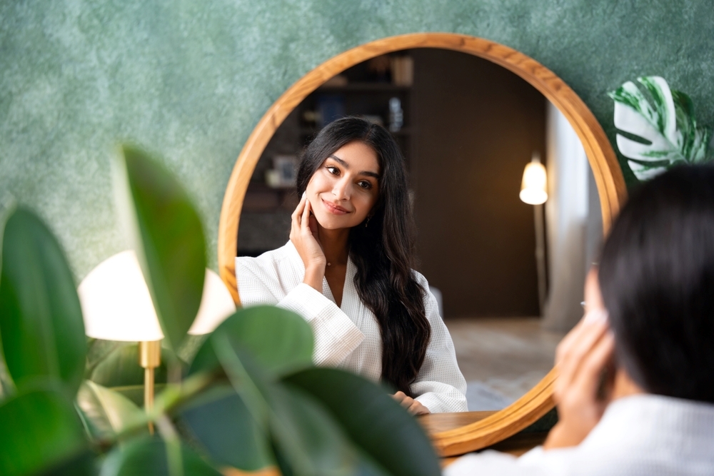 `alt="A woman in a gown smiles at herself in a mirror."`