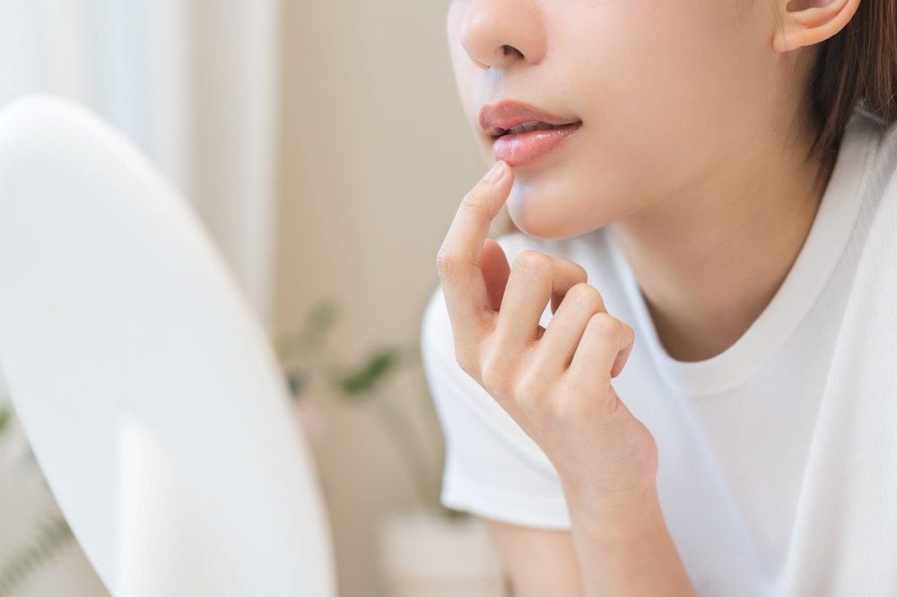 A woman touches her lips in front of a mirror.