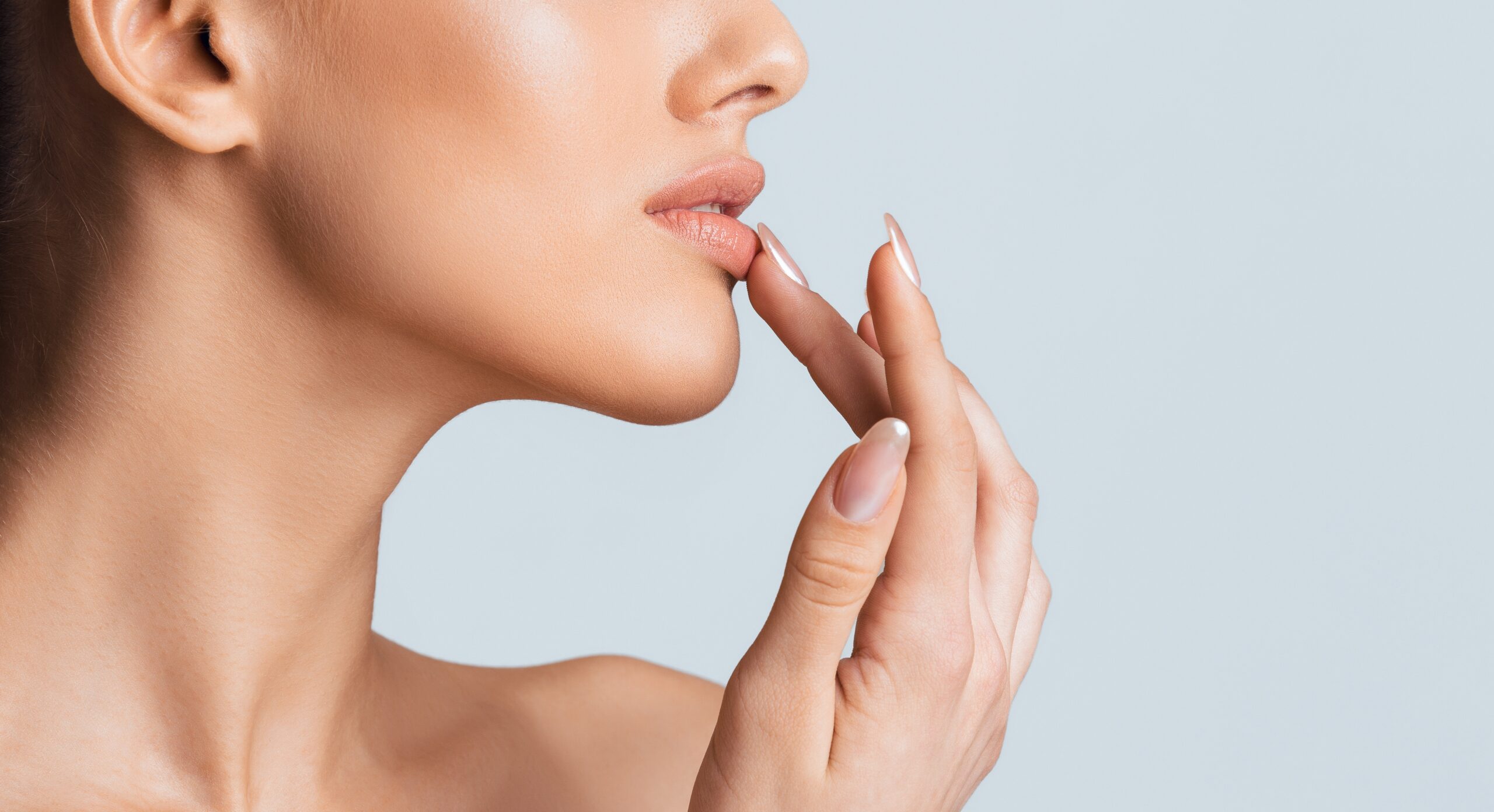 A woman touches her lower lip with her fingertips.
