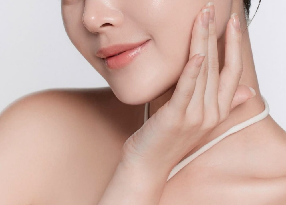 A woman smiles with her hand near her lips.