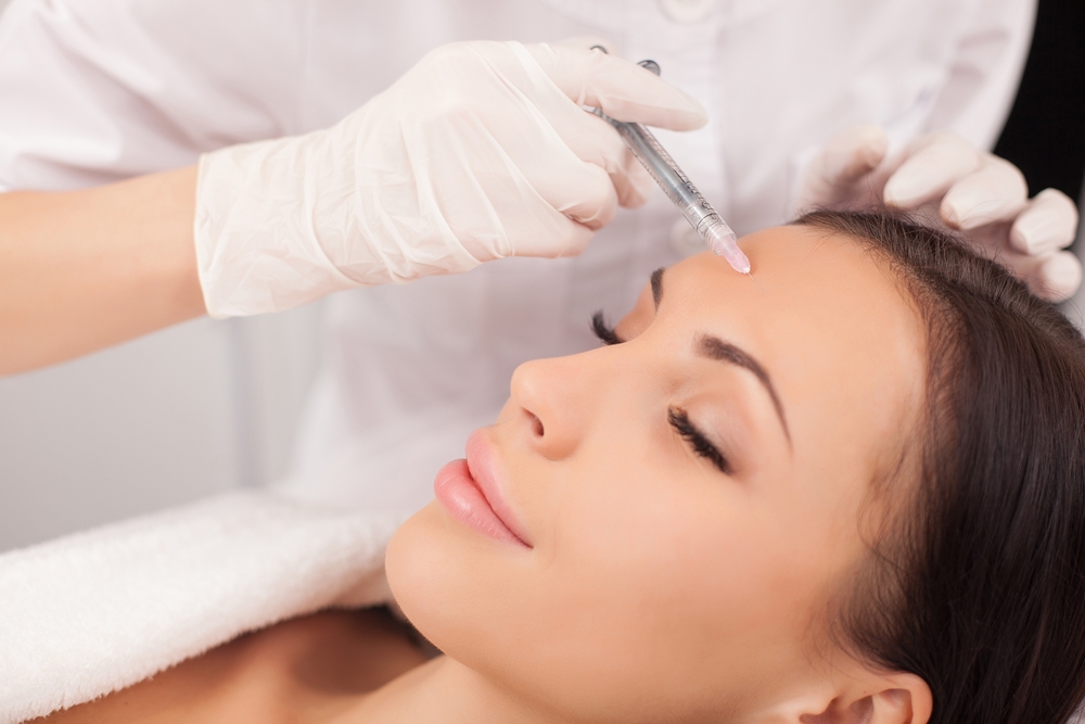 A woman receiving Botox injections in her forehead