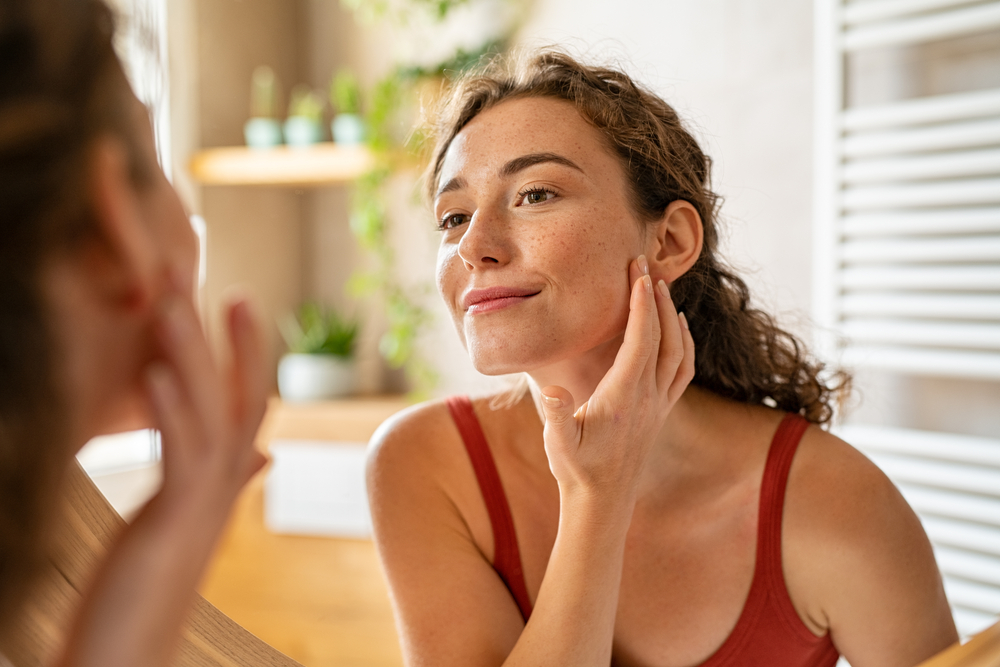 A woman checking her skin in the mirror
