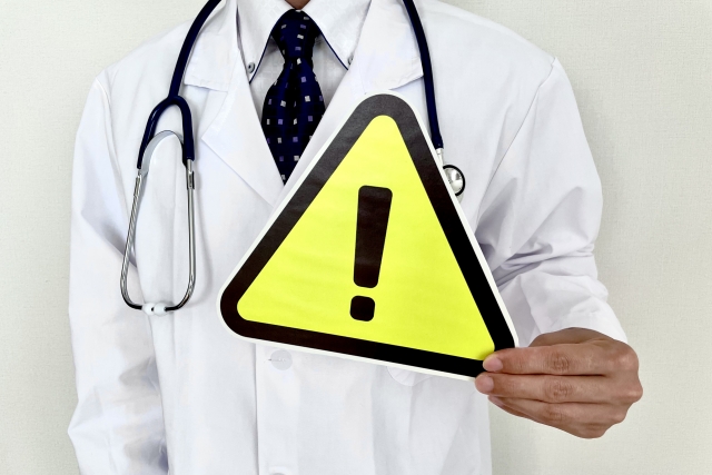 注意マークを持つ白衣の男性　おでこのヒアルロン酸は目元に落ちてくる？打つ前に知りたいデメリット｜NERO DOCTOR / BEAUTY（美容医療）