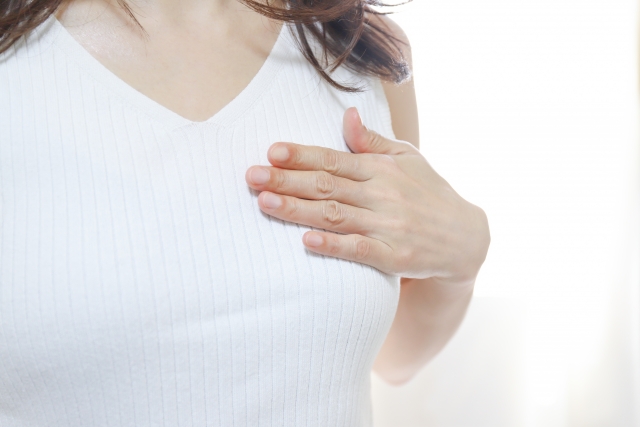 胸に手を当てる女性 脂肪豊胸ダウンタイムの症状や経過は?軽減のためにできることを解説|NERO DOCTOR / BEAUTY(美容医療)