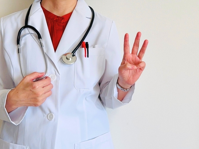 3本指を出す白衣を着た女性 豊胸の値段相場は?大手と中規模クリニックの費用感をチェック|NERO DOCTOR / BEAUTY(美容医療)