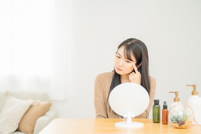 鏡を見て目元を気にする女性 眼瞼下垂と眉下切開の違いは?視界を広くするにはどちらを選べばいい?|NERO DOCTOR / BEAUTY(美容医療)
