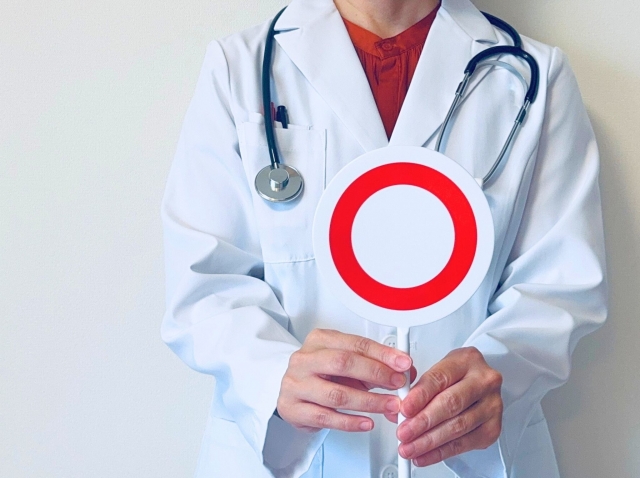 〇の札をあげる白衣の女性　ネックリフトとは？首のたるみ・シワを整える手術とリスク｜NERO DOCTOR / BEAUTY（美容医療）