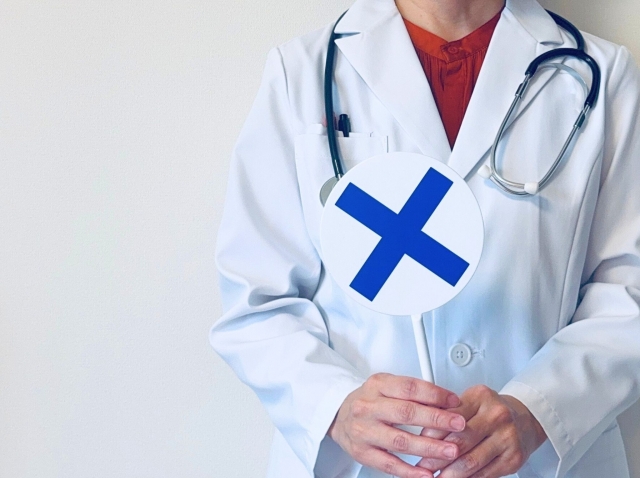 ×の札をあげる白衣の女性　ネックリフトとは？首のたるみ・シワを整える手術とリスク｜NERO DOCTOR / BEAUTY（美容医療）