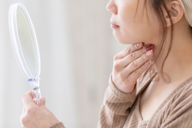 鏡を見ながら顎下に手を当てる女性　クォンタムとは？切らない“内側RFタイトニング”の仕組み・注意点｜NERO DOCTOR / BEAUTY（美容医療）