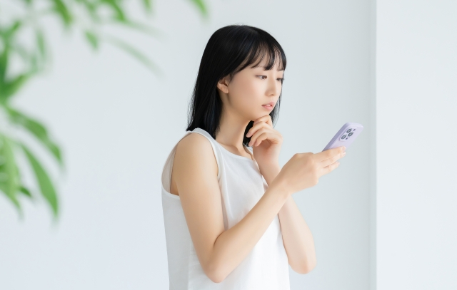 スマホで調べ物をする女性　ジュベルックの危険性は？リスク・避けたい施術条件まで解説｜NERO DOCTOR / BEAUTY（美容医療）