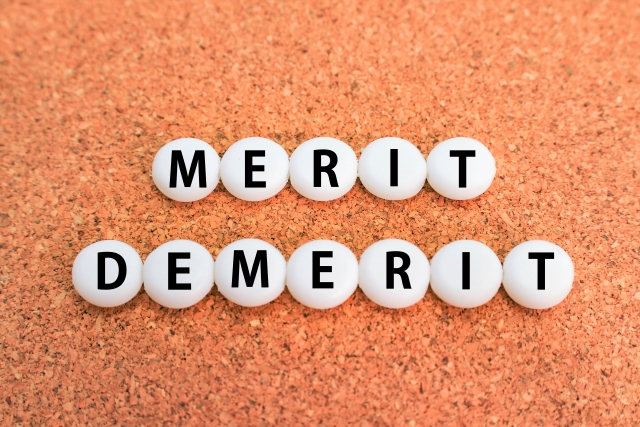 コルクボードに配置された「MERIT（メリット）」と「DEMERIT（デメリット）」の文字