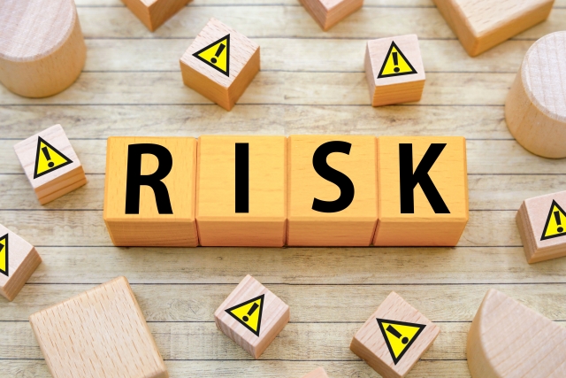おなかの脂肪吸引におけるリスクや副作用のイメージ（RISKの文字と注意マークのウッドブロック）