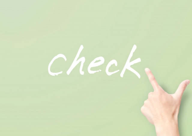 薄緑色の背景に白字で書かれた「check」の文字と、それを人差し指で指さす右手のアップ