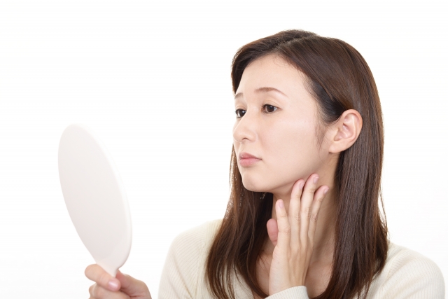 鏡でフェイスラインをチェックする女性