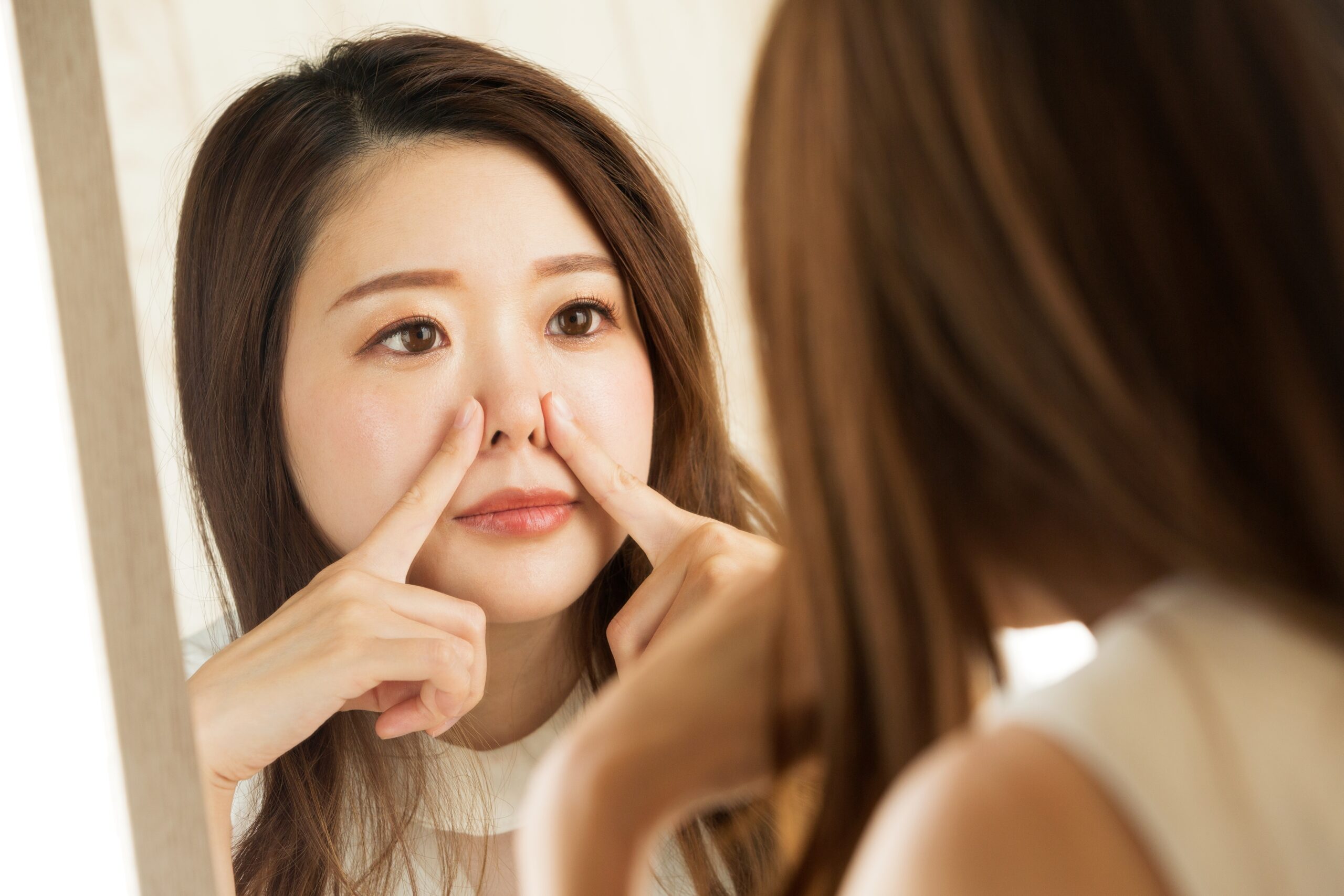 鼻筋を太くしたいと鏡を見ながら考える女性のイメージ画像
