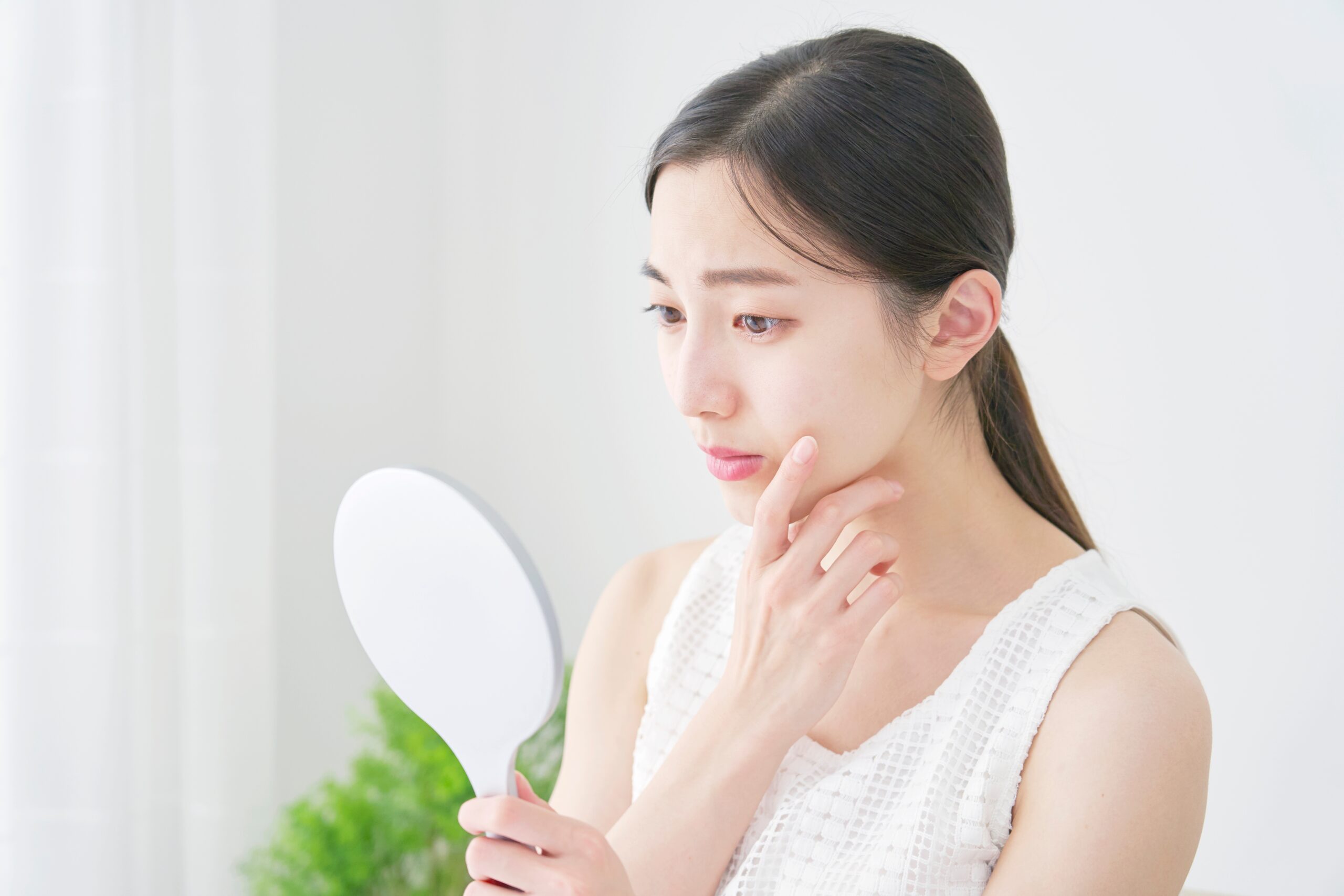 鏡をみて悩む女性